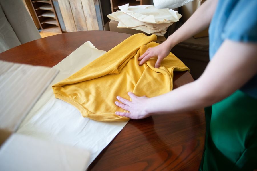 Hands folding a yellow shirt